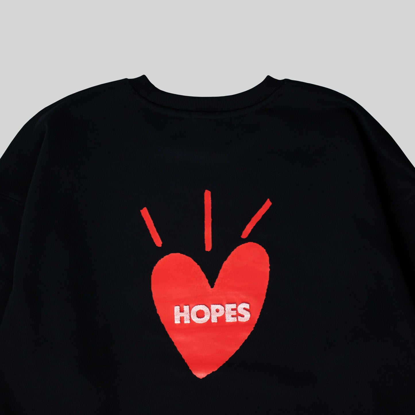 Close-up of the back of the Hopesbrands Big Heart crewneck sweatshirt, featuring red-toned toothbrush embroidery detailing on the printed big heart logo