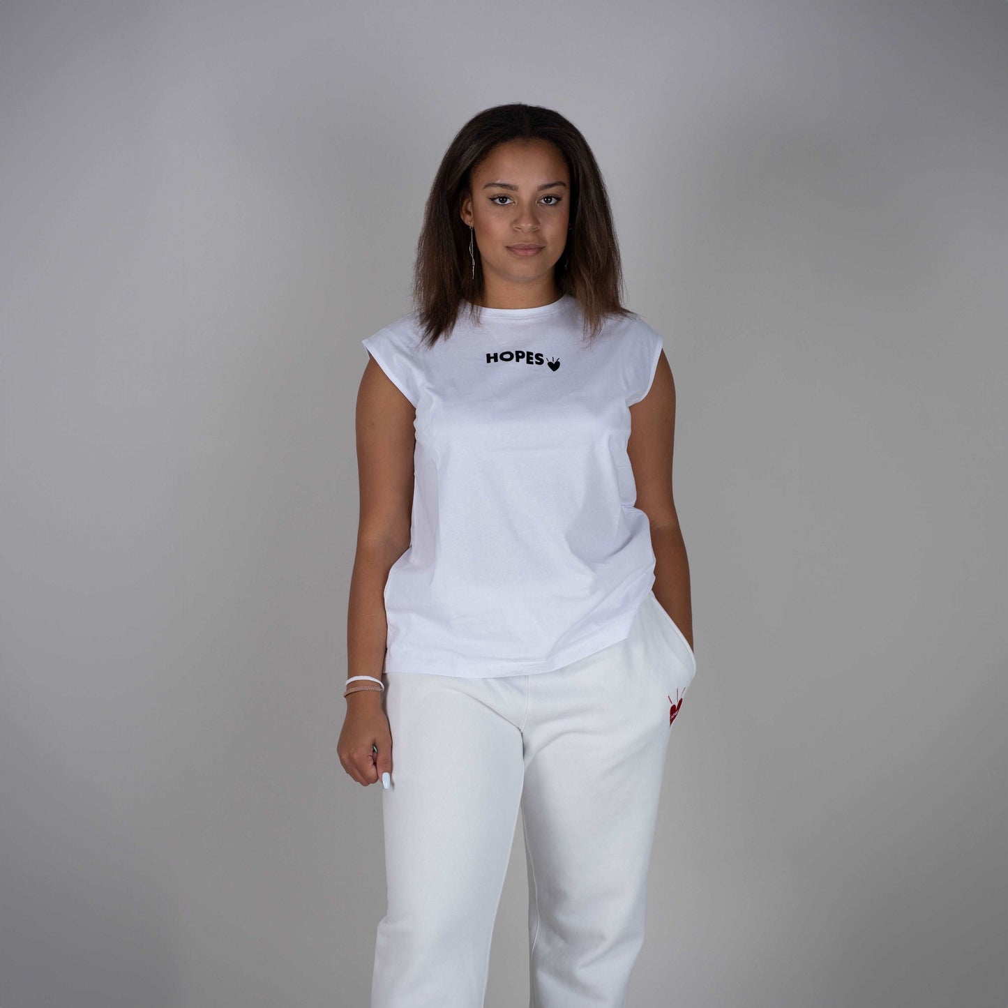 Model wearing the Hopesbrands white Cool Touch Tank Top, featuring a flocked Hopes logo on the chest. The sleek design emphasizes comfort and breathability, making it an ideal choice for everyday wear. This stylish tank top embodies a casual style, perfect for versatile layering.