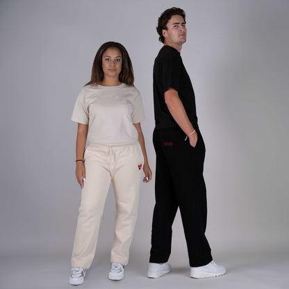 Models wearing Hopesbrands black and tan Big Heart sweatpants with embroidered logo on the left thigh. The unisex sweatpants offer a comfortable, stylish fit for everyday wear.