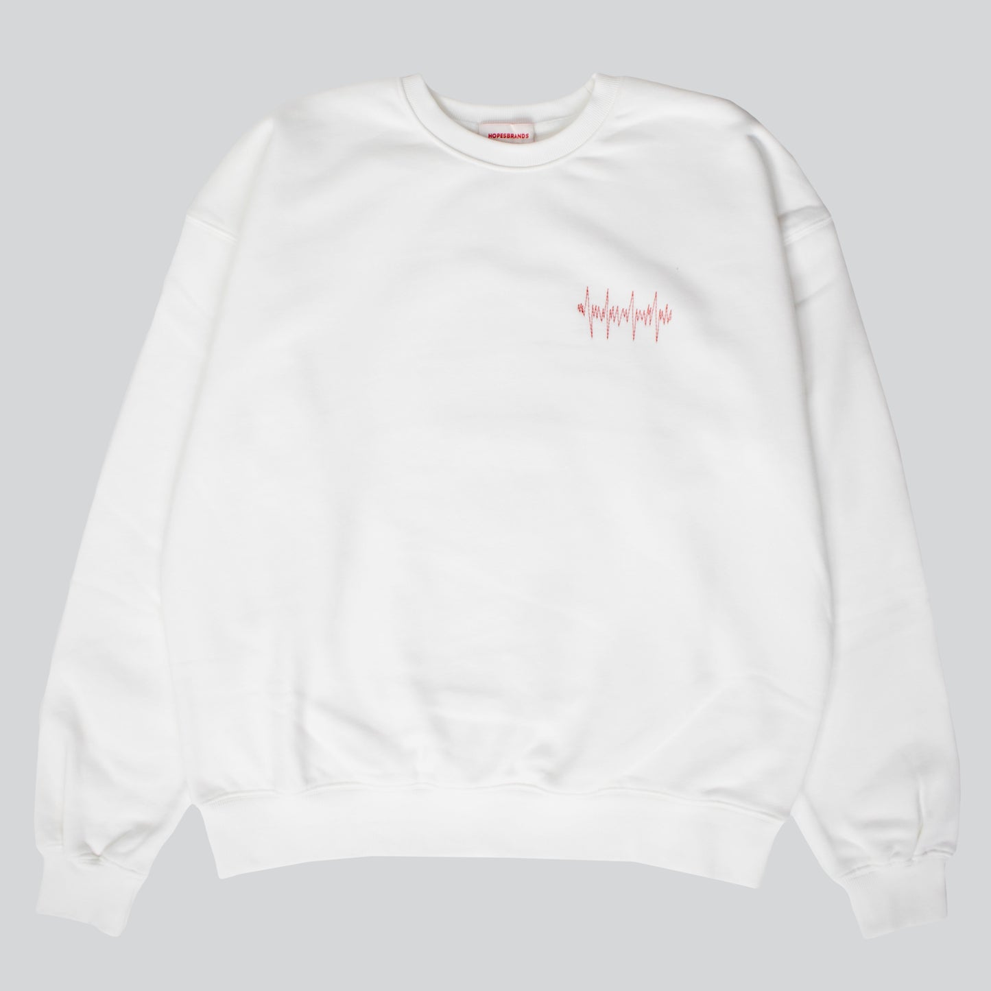 Product shot of the Hopesbrands Big Heart crewneck sweatshirt in off white, featuring red lifeline stitches on the left chest and crafted from a comfortable cotton blend.