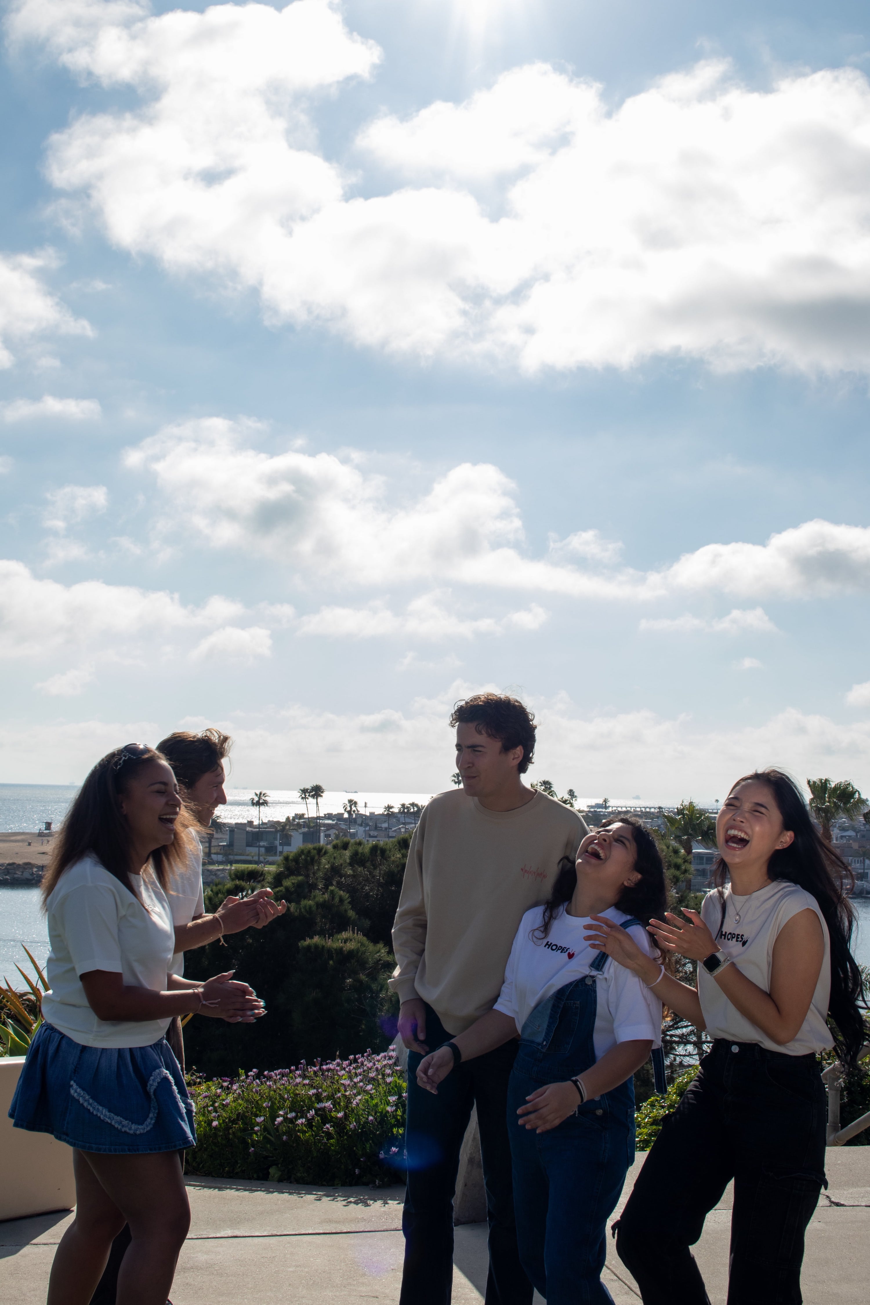 Group of friends wearing Hopesbrands apparel, laughing and enjoying a sunny day at the beach. The scene highlights the comfortable, casual fit of Hopesbrands' unisex pieces, embodying versatile, timeless style and a carefree vibe.